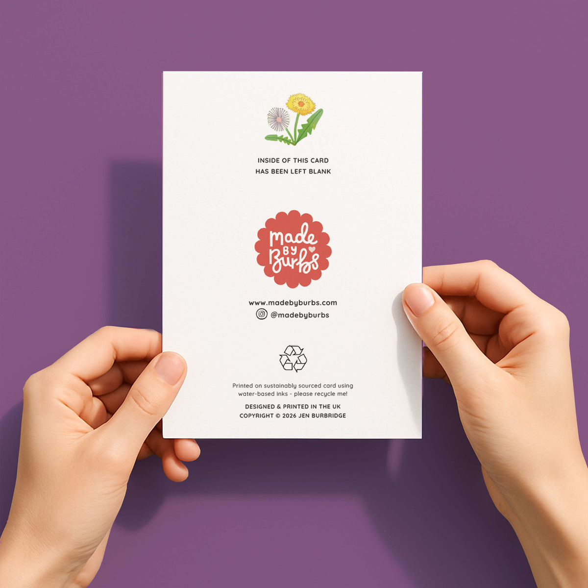 Back of the card with 'Made by Bubs' branding held by hands against a purple background